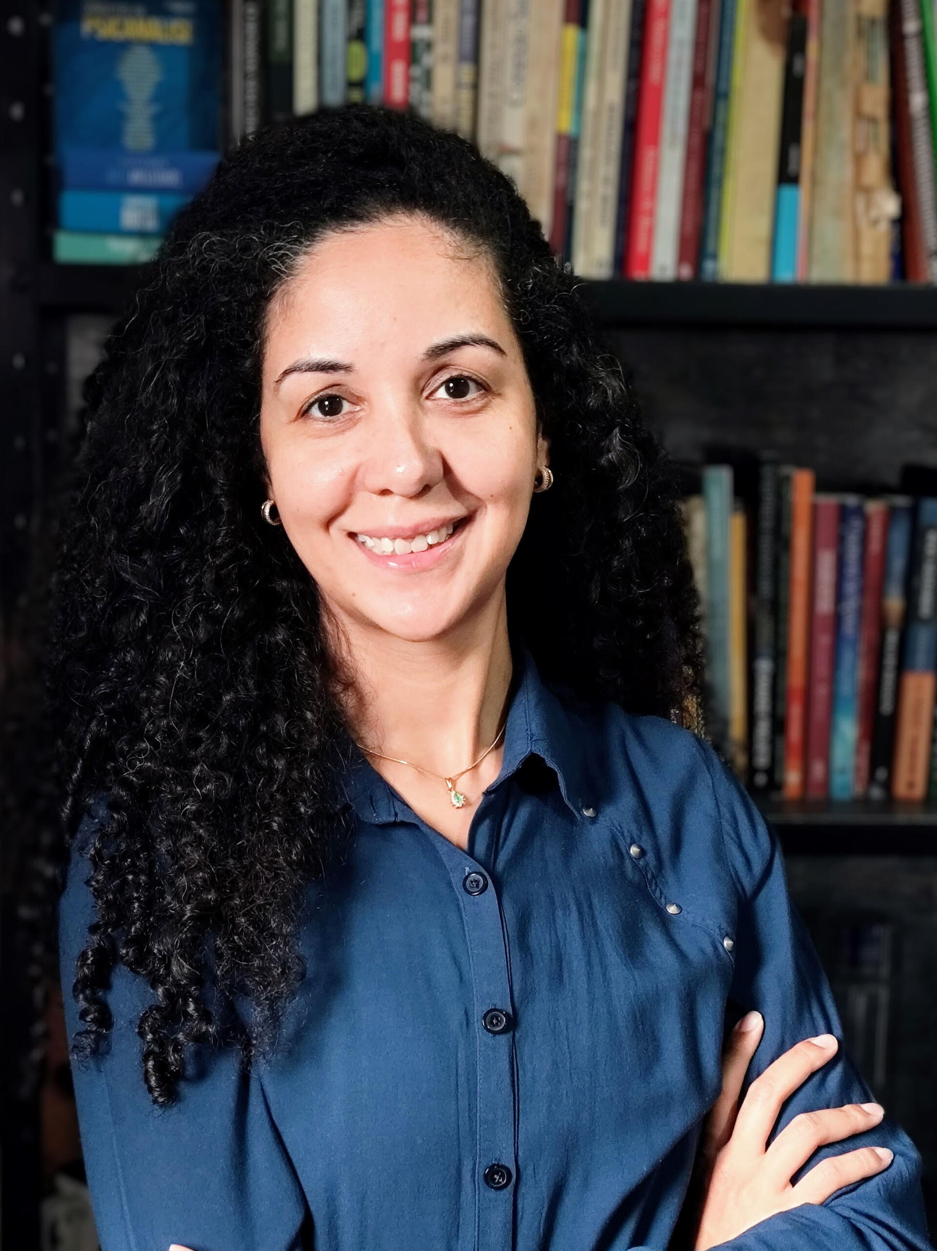 trajetoria-profissional-e-escuta-clinica Psicanalista Vanessa dos Anjos em espaço de estudos com livros de psicanálise, simbolizando a trajetória profissional e a escrita de colunas sobre o inconsciente.